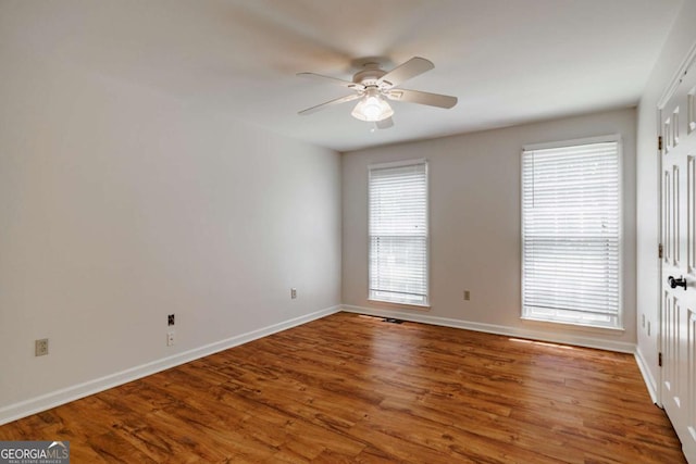spare room with ceiling fan, wood finished floors, and baseboards