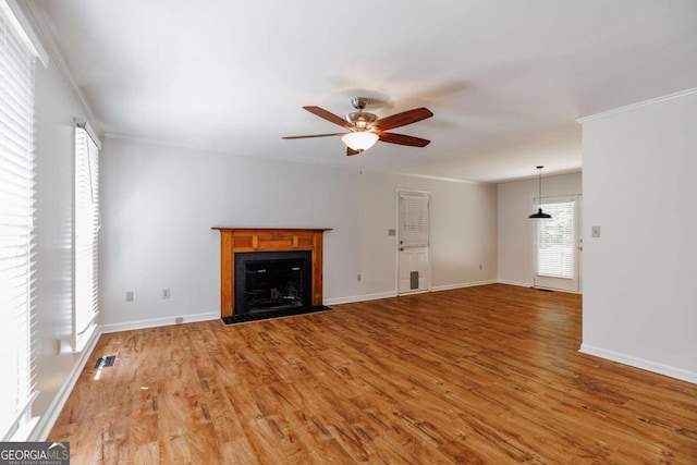 unfurnished living room featuring a ceiling fan, light wood-style flooring, a fireplace with flush hearth, baseboards, and ornamental molding
