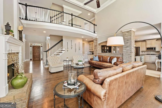 3456 Glen Mist Pl, Dacula, GA 30019 - living room featuring a towering ceiling, wood finished floors, a lit fireplace, ornate columns, and baseboards