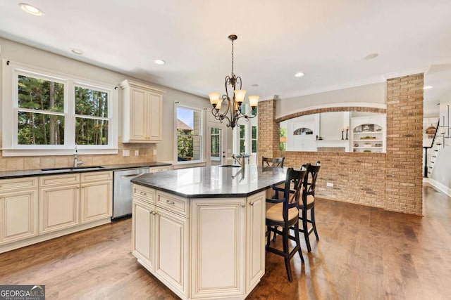 3456 Glen Mist Pl, Dacula, GA 30019 - kitchen with cream cabinetry, stainless steel dishwasher, a chandelier, a breakfast bar area, and brick wall