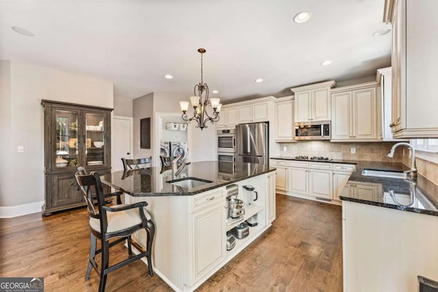 3456 Glen Mist Pl, Dacula, GA 30019 - kitchen with washing machine and dryer, appliances with stainless steel finishes, a sink, a chandelier, and dark stone countertops