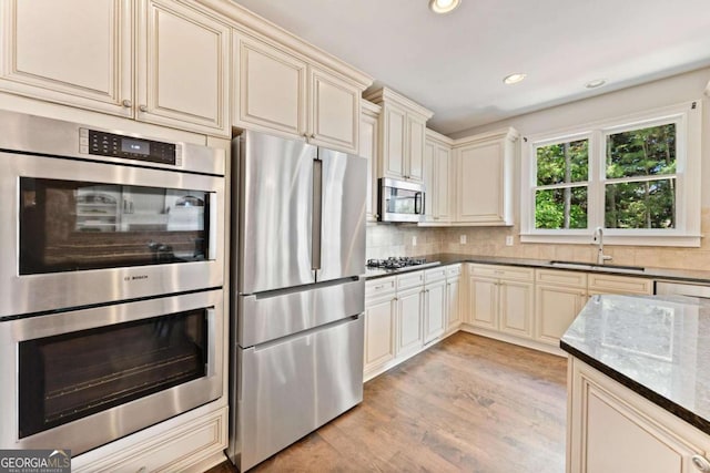 3456 Glen Mist Pl, Dacula, GA 30019 - kitchen featuring appliances with stainless steel finishes, cream cabinets, dark stone countertops, a sink, and recessed lighting