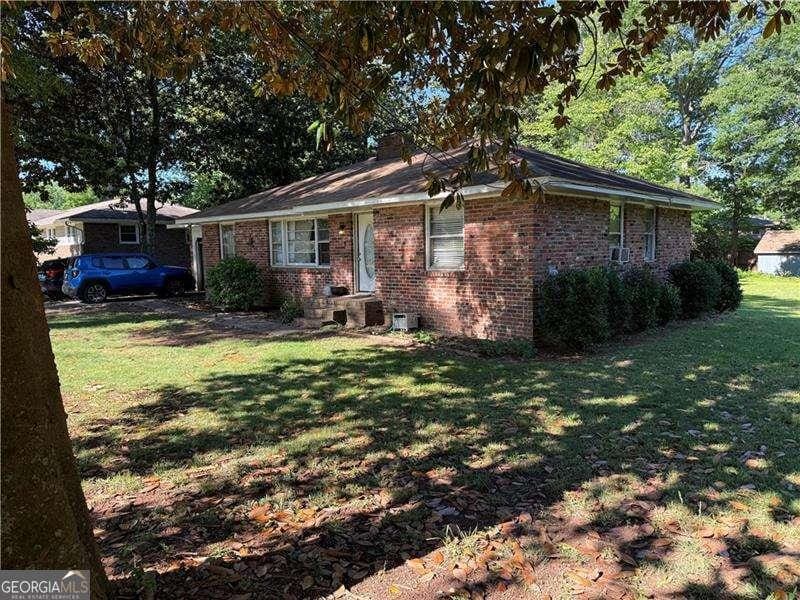 single story home with a front lawn, brick siding, and a chimney