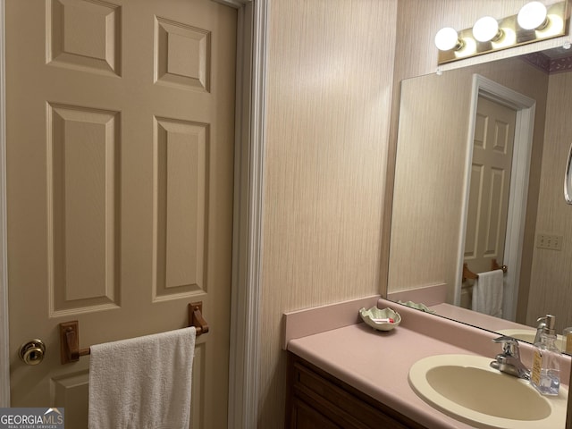 bathroom with wallpapered walls and vanity