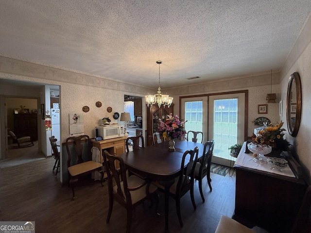 dining space with a textured ceiling, wood finished floors, and a chandelier
