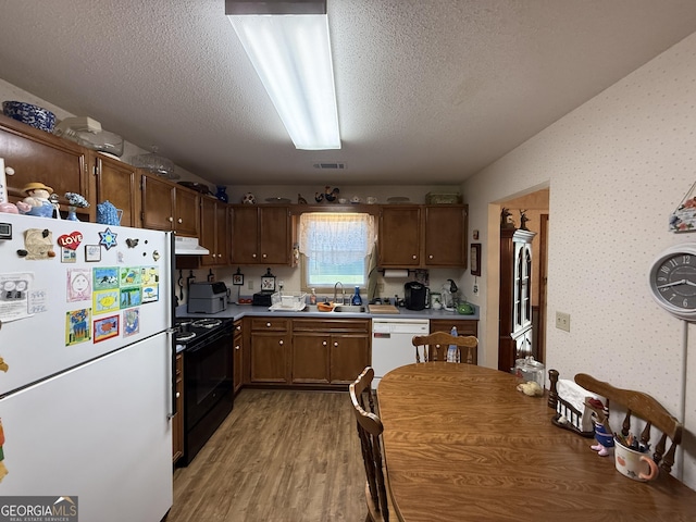 kitchen featuring white appliances, a sink, extractor fan, light wood-style flooring, and a textured ceiling