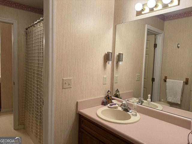 full bath with wallpapered walls and vanity