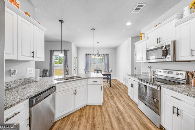 145 Gavin Way, Rincon, GA 31326 - kitchen with stainless steel appliances, a sink, light wood-style flooring, a peninsula, and white cabinetry