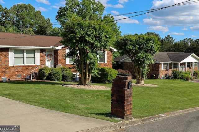 view of front facade with brick siding and a front lawn