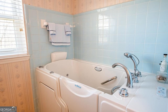 bathroom with wallpapered walls and a whirlpool tub