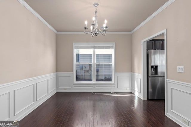 unfurnished dining area featuring a chandelier, crown molding, wainscoting, and dark wood-style flooring
