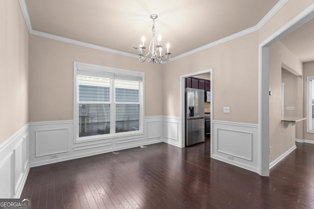 unfurnished dining area with a chandelier, dark wood-style flooring, wainscoting, and crown molding