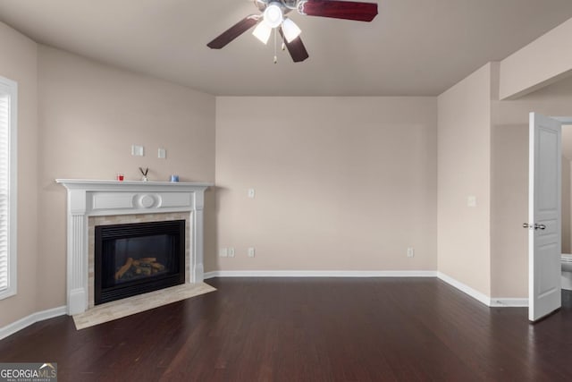 unfurnished living room featuring wood finished floors, ceiling fan, a tiled fireplace, and baseboards