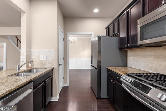 kitchen with appliances with stainless steel finishes, a sink, light stone countertops, dark wood finished floors, and recessed lighting
