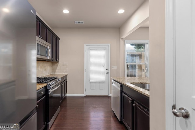 kitchen featuring stainless steel appliances, backsplash, dark wood finished floors, light stone counters, and recessed lighting