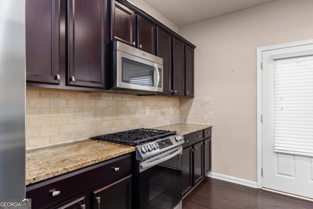 kitchen with stainless steel appliances, baseboards, dark wood finished floors, backsplash, and light stone counters