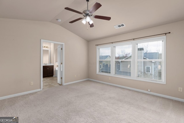 unfurnished bedroom with vaulted ceiling, light carpet, baseboards, ensuite bath, and a ceiling fan