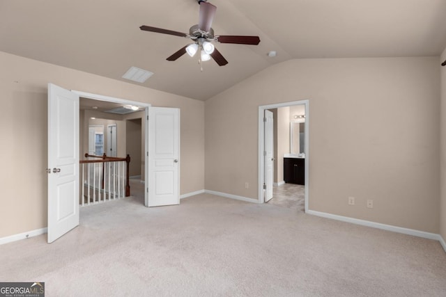 unfurnished bedroom with light colored carpet, lofted ceiling, baseboards, ensuite bathroom, and ceiling fan