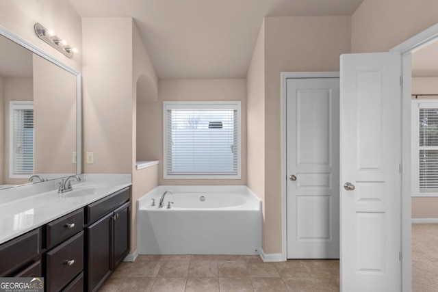 full bath featuring a bath, vanity, baseboards, and tile patterned floors