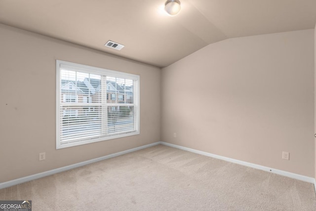 spare room with carpet flooring, vaulted ceiling, and baseboards