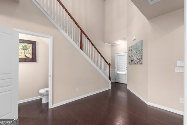 foyer entrance with a towering ceiling, hardwood / wood-style flooring, stairway, and baseboards