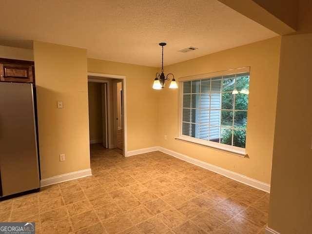 2506 Wateringhole Ct, Statesboro, GA 30458 - unfurnished dining area featuring a chandelier, baseboards, and a textured ceiling