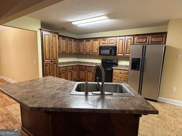 2506 Wateringhole Ct, Statesboro, GA 30458 - kitchen featuring black appliances, a sink, baseboards, a kitchen island with sink, and dark countertops