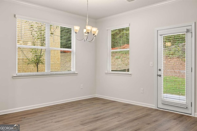 unfurnished dining area with a chandelier, plenty of natural light, wood finished floors, and ornamental molding