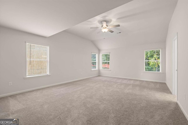 carpeted empty room featuring healthy amount of natural light, a ceiling fan, baseboards, and vaulted ceiling
