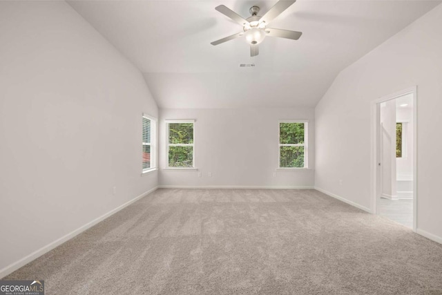 carpeted spare room featuring vaulted ceiling, plenty of natural light, ceiling fan, and baseboards