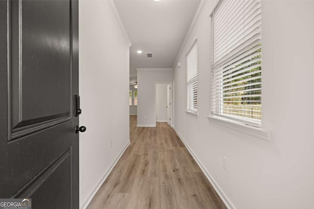 hallway featuring crown molding, baseboards, light wood-style floors, plenty of natural light, and recessed lighting