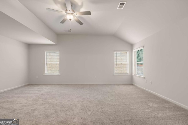 carpeted empty room with a ceiling fan, baseboards, and vaulted ceiling