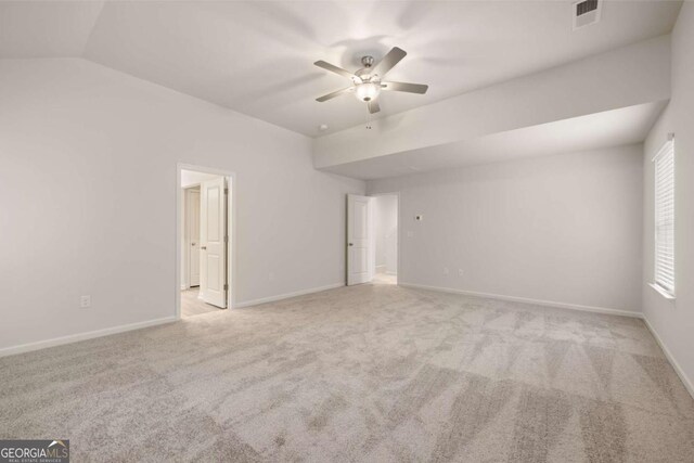 carpeted spare room featuring ceiling fan, baseboards, and lofted ceiling