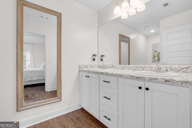 full bathroom with wood finished floors, baseboards, double vanity, and ensuite bathroom