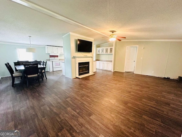 living area with a textured ceiling, dark wood-style floors, crown molding, ceiling fan, and a glass covered fireplace