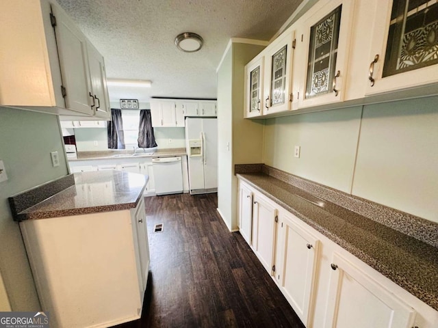 kitchen featuring white appliances, dark wood finished floors, glass insert cabinets, a textured ceiling, and white cabinetry