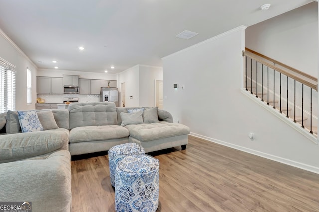living room with crown molding, light wood-style flooring, baseboards, and recessed lighting