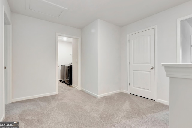 carpeted empty room with attic access and baseboards