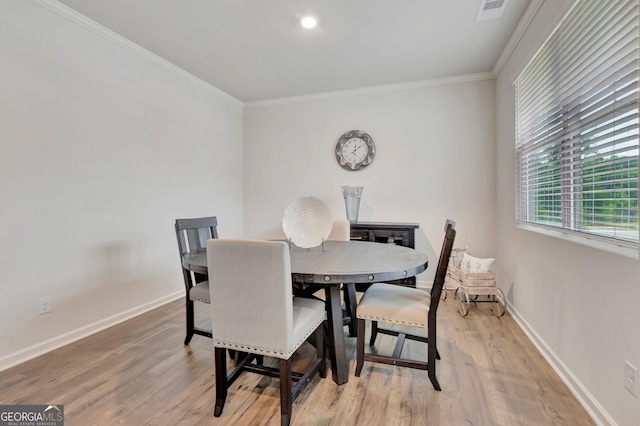 dining room featuring ornamental molding, light wood-type flooring, and baseboards