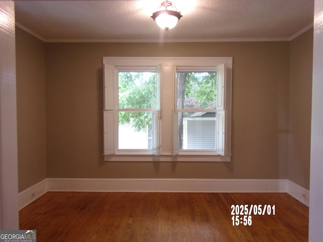 spare room featuring wood finished floors, ornamental molding, and baseboards