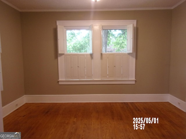 unfurnished room with wood finished floors, baseboards, and crown molding