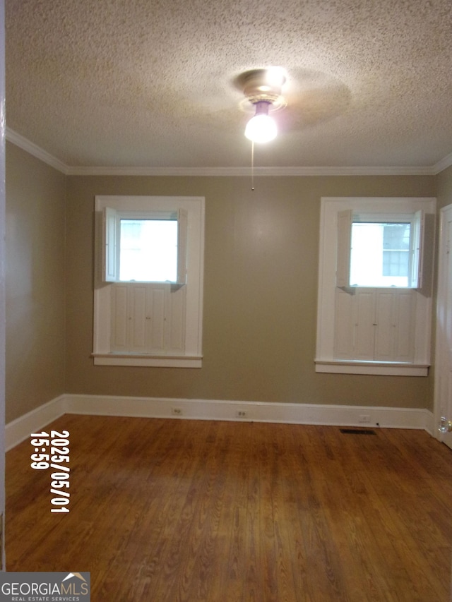 spare room featuring a textured ceiling, wood finished floors, a ceiling fan, baseboards, and ornamental molding