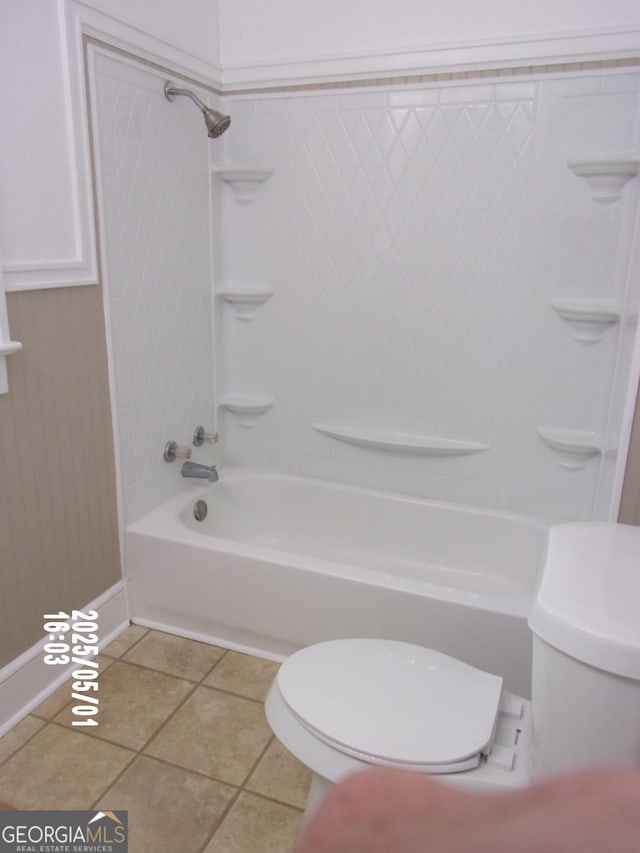 bathroom with toilet, bathing tub / shower combination, tile patterned flooring, and baseboards