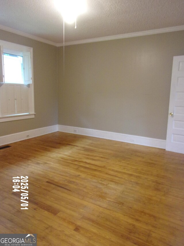 unfurnished room featuring light wood-style flooring, ornamental molding, a textured ceiling, and baseboards