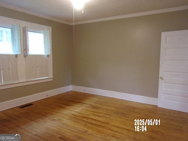 spare room with crown molding, wood finished floors, baseboards, and a textured ceiling