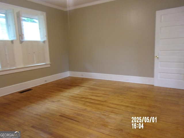 unfurnished room with crown molding, wood finished floors, and baseboards