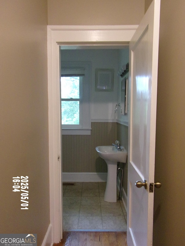 bathroom featuring baseboards, wainscoting, and a sink