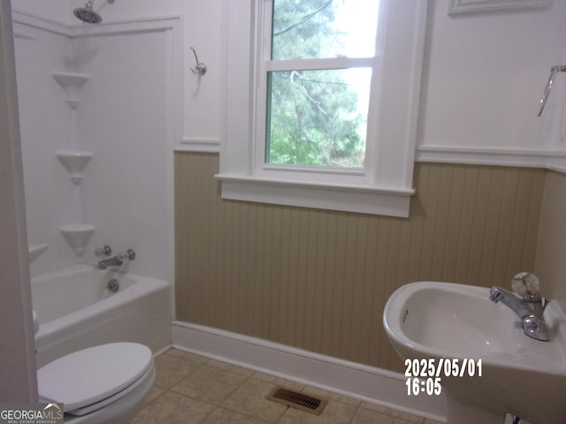 full bath featuring plenty of natural light, toilet, tub / shower combination, wainscoting, and a sink