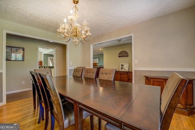637 Lakeview Dr, Newborn, GA 30056 - dining room featuring a chandelier, light wood finished floors, a textured ceiling, and baseboards