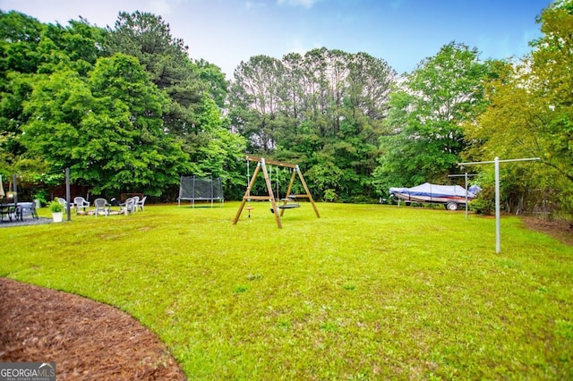 4529 Lakeview Dr, Powder Springs, GA 30127 - view of grassy yard with a trampoline, a playground, a patio area, and view of wooded area
